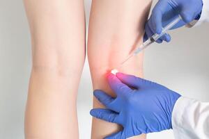 The doctor makes an injection into the periarticular tissue, in which there is pain behind the knee and intravascular pathologies, close-up photo