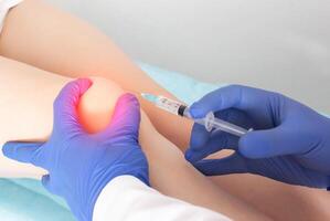 The doctor injects injections with hyaluronic acid into the knee joint of a patient who has pain and arthrosis in the knee. Concept of joint treatment with chondroprotectors, close-up photo