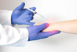A doctor rheumatologist performs a wrist block on a patient who has pain and inflammation in the joint. Concept of injections with local anesthetic and chondroprotectors, close-up photo