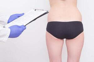 A plastic surgeon examines a patient s buttocks before installing silicone implants. The concept of buttock enlargement, shaping and volume, figure correction photo
