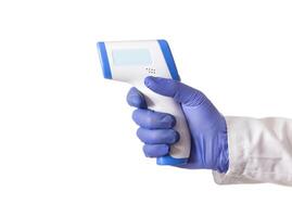 Doctor's hand in a medical glove holds an infrared thermometer on a white background, isolate. The concept of increasing body temperature in case of diseases photo