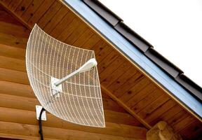 Parabolic antenna for amplifying the signal of cellular communication and the Internet installed in a country house. Strengthening the 4G and 5G Internet signal in the country, close-up photo