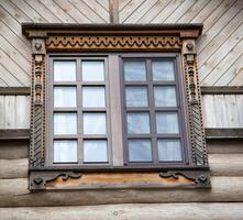 A beautiful square window with carved shutters. Rustic decoration, close-up photo