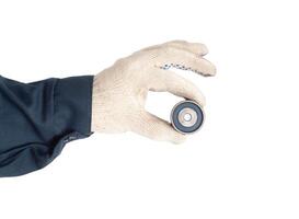 A car mechanic holds a small used timing belt roller on the car's engine. Timing belt rollers replacement schedule, isolate photo