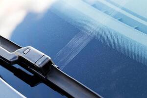 Scratch on car windshield from cleaning worn out wipers, close-up photo