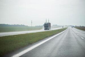 Traffic from cars drives on a highway slippery from rain in cloudy rainy weather. Copy space for text photo