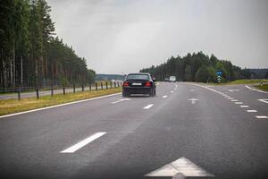 Traffic from cars drives on a highway slippery from rain in cloudy rainy weather. Copy space for text photo
