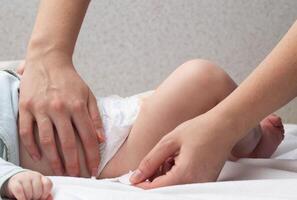 The mother fastens the fasteners and changes the baby's diaper, close-up. Copy space for text photo