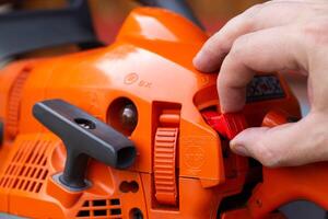 Opening and closing the throttle by moving the combination lever up one detent position to start the chainsaw engine. Close-up, industry photo