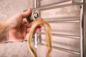 Fitting and sanitary flax in hand against the background of a heated towel rail. The concept of using linen in plumbing against water leaks. Close-up photo