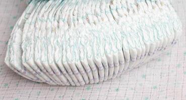 Many stacks of baby soft and comfortable diapers on a white background, close-up photo