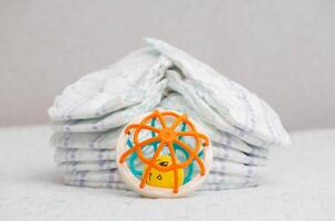 Baby toy on the background of a stack of baby diapers, close-up. Copy space for text photo