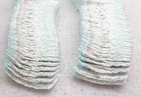 Many stacks of baby soft and comfortable diapers on a white background, close-up photo