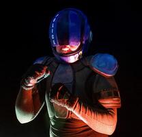 Cyberpunk future concept. Police officer stands in boxing pose and waves and punches his fits in dark. Halfman robot is ready for fight. Bionic cyborg looks at camera. Science fiction scene, sci photo