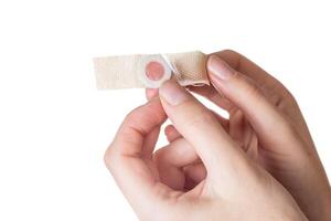 The girl holds in her hands a plaster against core calluses on her legs. White background, isolate, close-up photo