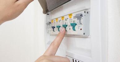 A person turns on an electric semi-automatic device with his finger to turn on the current in the electricity distribution board. Distribution box photo