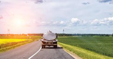 The tanker truck transports milk on the background of the fields. Logistics and business in agriculture. Copy space for text, industry, countryside photo