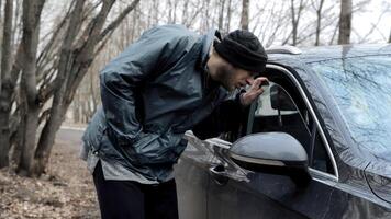 Homeless man walks up to someone else's car, male burglar robber looks through the slightly open window of auto's door and walks away. Vehicle with alarm system. Property insurance against theft crime photo