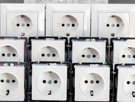 Many modern electrical sockets on a gray background, close-up. Rise in the price of electricity price per kilowatt, saving electricity, close-up photo