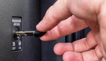 Man turns off front passenger airbag with key, macro photo
