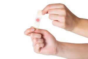 The girl holds in her hands a plaster against core calluses on her legs. White background, isolate, close-up photo