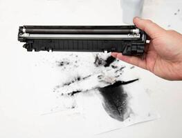 A man holds a refilled laser printer cartridge in his hand against the background of using old toner. Refilling the cartridge at home photo
