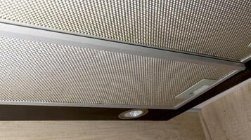 Modern kitchen hood with grease filter for air purification. Replacing the grease filter and maintaining the kitchen hood. photo