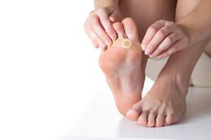 Woman sticks a medical plaster to the plantar wart of the leg to remove dead skin and calluses. Copy space for text photo
