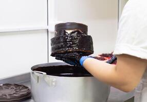 the confectioner makes a chocolate cake, pours chocolate on the biscuit cakes, handmade. Cake Making, torte photo