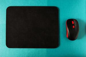 Computer mat and computer mouse on a turquoise background, close-up, instrument photo