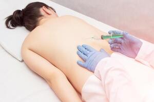 The doctor makes a patient a girl an injection of a blockage in the spine to eliminate back pain, an injection with chondroprotekrom, treatment of the spine, inflammation photo