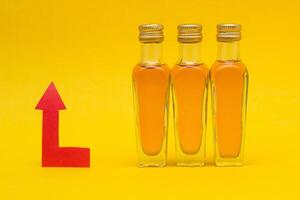 Small bottles of alcohol on a yellow background and a red arrow concept of raising the price of alcohol, close-up, markup photo
