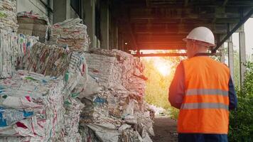 A worker in a signal vest checks the amount of pressed and recycled garbage, waste recycling photo