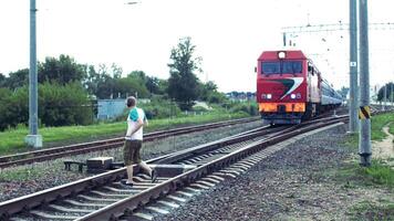 A caucasian man in headphones listens to music and crosses the railway right under the train, danger on the railway photo