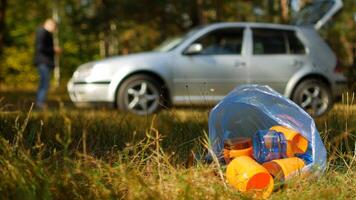 A car in the forest and a package of garbage in the foreground, outdoor recreation and forest pollution, background photo
