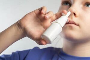 A girl sprays a spray against runny nose and nasal congestion into her sinuses. Treatment of sinusitis and sinusitis, antimicrobial spray, close-up photo