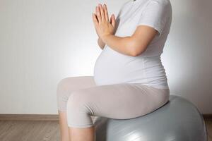 Relaxation and meditation for a pregnant girl on a fitball ball on a white background. Women Health. Copy space for text photo