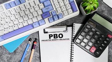 Concept of PBO - Projected Benefit Obligation write on paperwork isolated on Wooden Table. photo