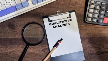 Concept of Qualitative Analysis write on paperwork isolated on Wooden Table. photo