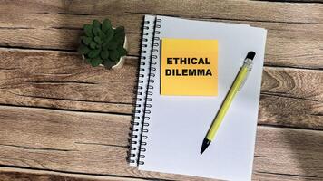 Concept of Ethical Dilemma write on sticky notes isolated on Wooden Table. photo