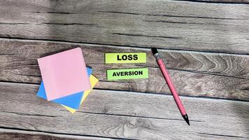 Concept of Loss Aversion write on sticky notes isolated on Wooden Table. photo