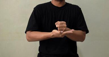 Young man showing word CRUCIFY in sign language on gray background photo