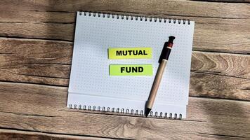 Concept of Mutual Fund write on sticky notes isolated on Wooden Table. photo
