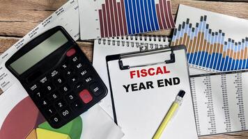Concept of Fiscal Year End write on paperwork isolated on Wooden Table. photo