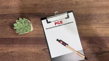 Concept of PCE - Personal Consumption Expenditures write on paperwork isolated on Wooden Table. photo