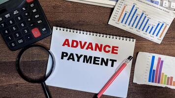 Concept of Advance Payment write on book isolated on Wooden Table. photo