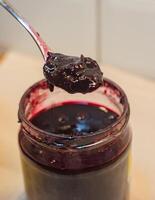 A spoon dipped into a jar of homemade wild berry jam. High quality photo
