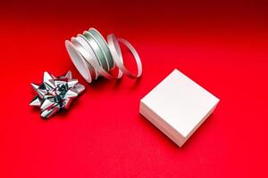 a white box with a bow and ribbon on a red background photo