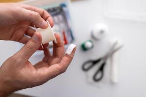 concept of first aid for cuts and injuries.a person is using a piece of tape photo