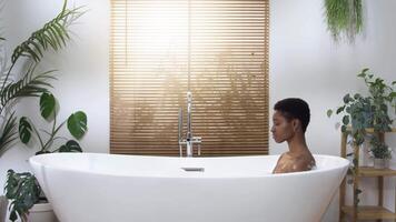 Attractive woman relaxing in foam luxury bath during a sunny morning routine. Rest and joy concept. video